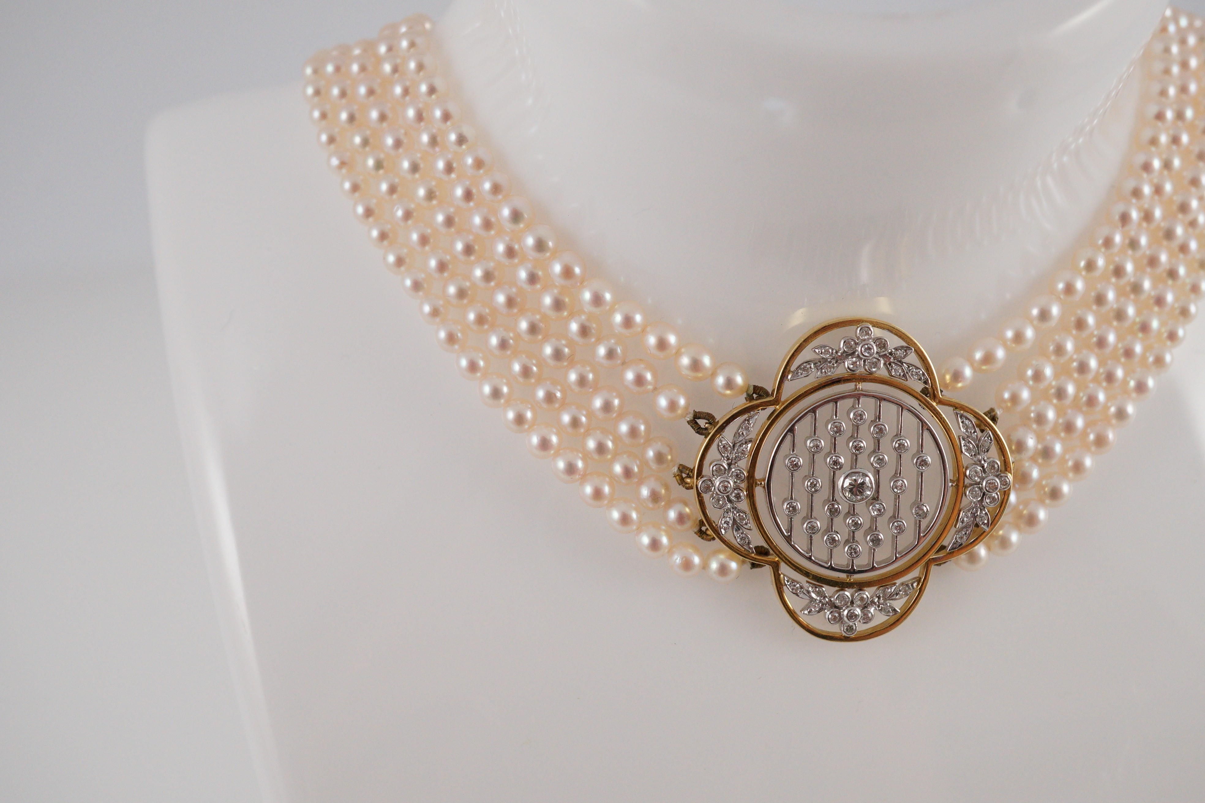 A quintuple strand seed pearl choker necklace, with pierced gold, platinum and diamond cluster set quatrefoil shaped clasp